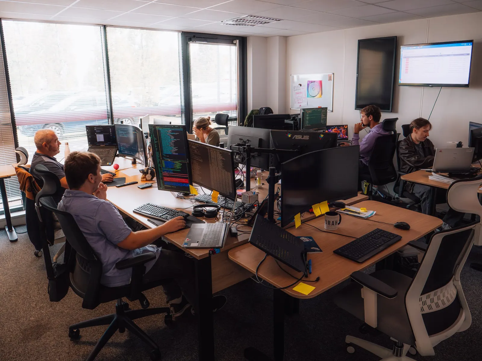 L'équipe technique d'E-learning Touch' au travail dans l'open space, chacun devant plusieurs écrans.
